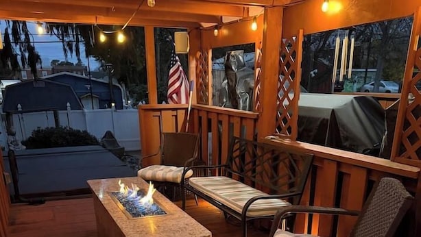 Eine Holzterrasse mit Feuerstelle, Gartenmöbeln und Lichterketten.