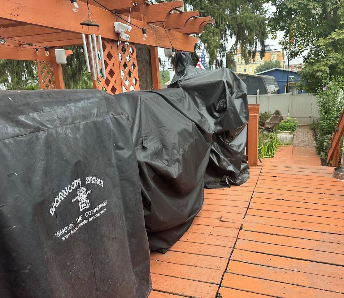 A covered outdoor seating area with a wooden pergola and a brick pathway.