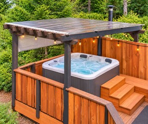 Un bain à remous doté d’une terrasse en bois et d’escaliers, entouré de verdure.