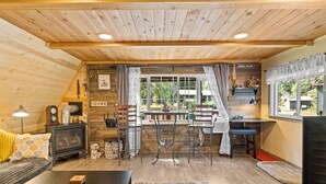 A cozy cabin interior with a dining area, wooden walls, and a view of the outdoors. - A-Frame @ Entrance to Rainier w/ Hot Tub & WiFi (Ashford)