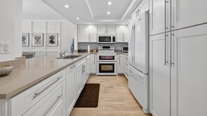 Une cuisine moderne avec des meubles blancs, un four à micro-ondes, un four et un réfrigérateur.
