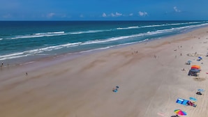 Une plage avec une vaste étendue de sable, un ciel bleu dégagé et une mer calme.