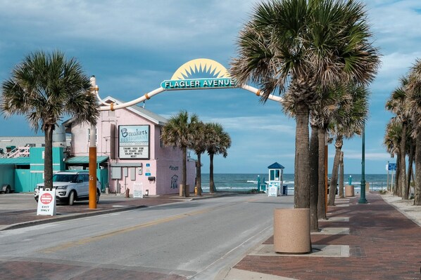 Vista de una calle con un edificio que dice 'Flagler Avenue' y un letrero de 'Breakers Restaurant'.