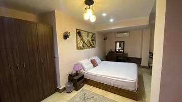Un dormitorio con cama, mesita de noche, lámpara y un armario de madera.