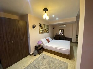 Un dormitorio con cama, mesita de noche, lámpara y un armario de madera.