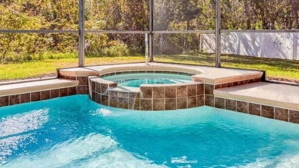 A swimming pool with a hot tub and a stone border.