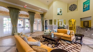 A spacious lobby with a yellow sofa, a coffee table, and a patterned rug.