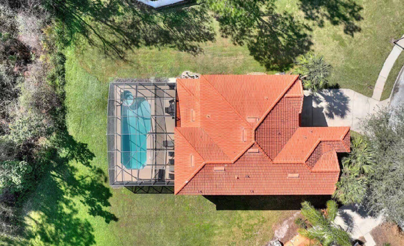 An aerial view of a building with a swimming pool and a large, red-roofed structure.