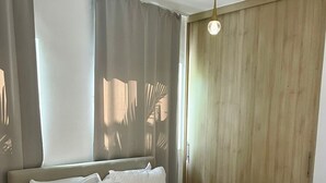 Un lit bien fait, avec une serviette, une armoire en bois et un luminaire suspendu.