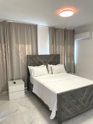 Un dormitorio moderno con una cama, una mesita de noche y un equipo de aire acondicionado.
