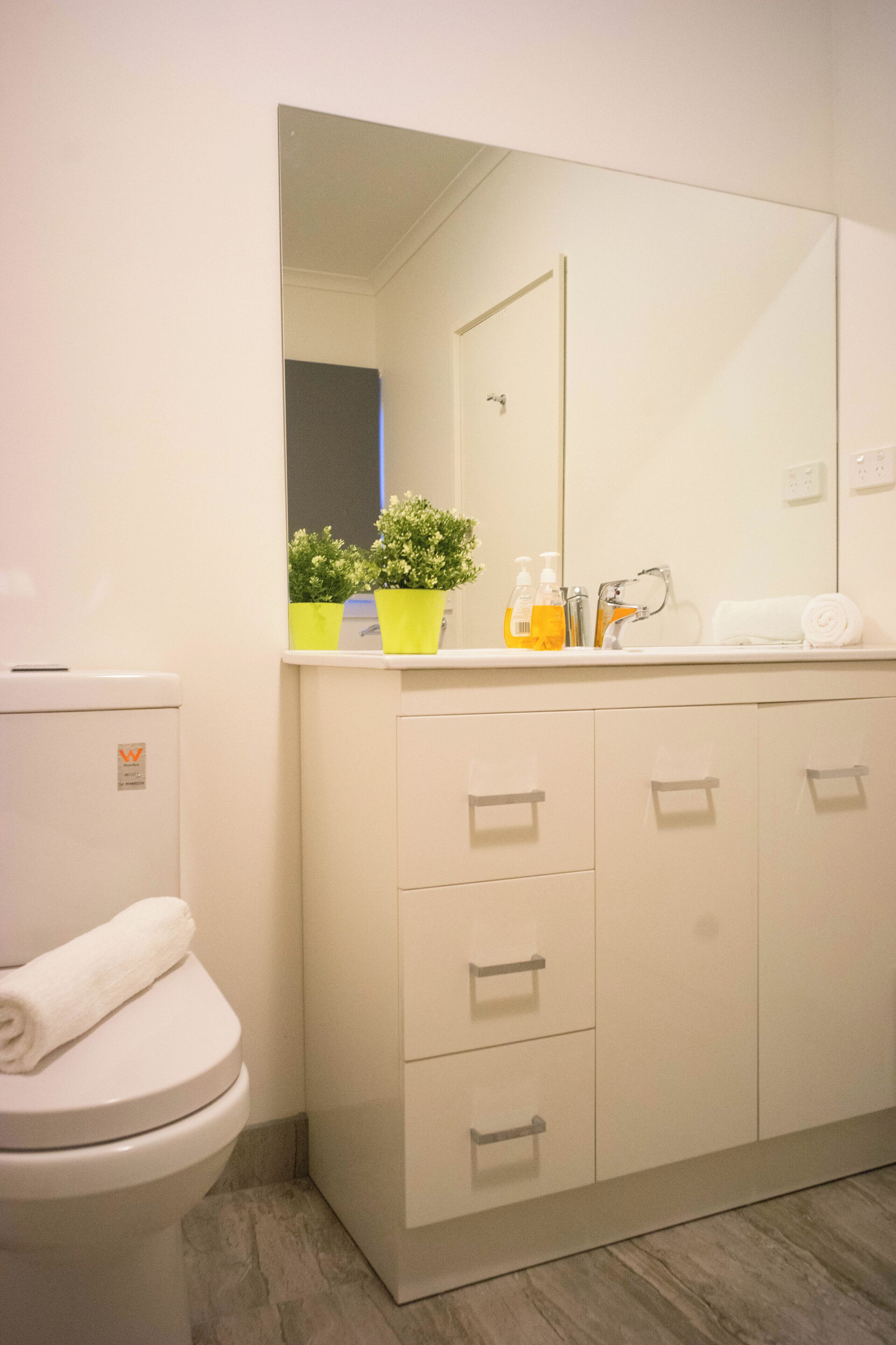 Ein modernes Badezimmer mit Toilette, Waschbecken, Spiegel und Schrank.