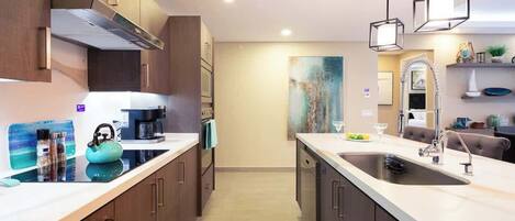 A modern kitchen with wooden cabinets, a central island, and pendant lighting.