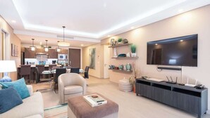 A modern living room with a sofa, ottoman, and a flat-screen TV.