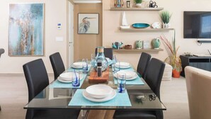 A dining area with a glass table, black chairs, and a variety of decorative items on shelves.