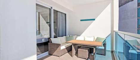 Un balcon avec un canapé, une table et des meubles en osier.