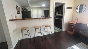 Une cuisine avec des tabourets en bois, un comptoir de bar et un coin repas agrémenté d’un tapis.