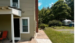 Une maison d’habitation avec un porche à l’avant, un petit garage attenant et une pelouse.