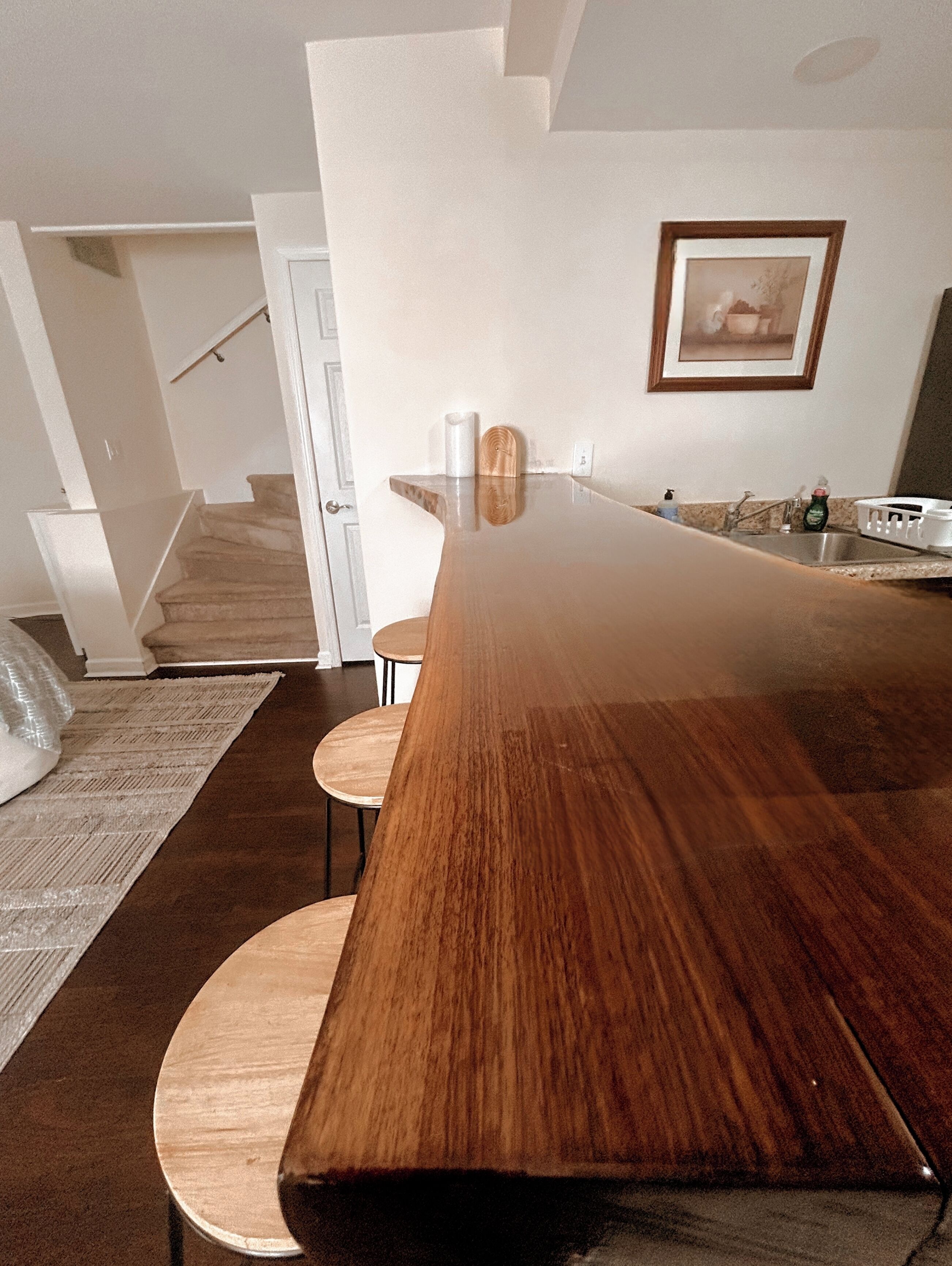 Una cocina moderna con una isla grande de madera, horno empotrado y pileta de acero inoxidable.