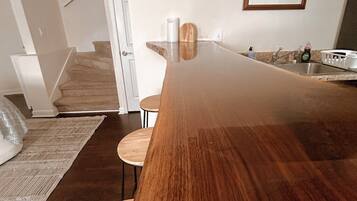 Una cocina moderna con una isla grande de madera, horno empotrado y pileta de acero inoxidable.