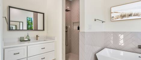 A modern bathroom with a large mirror, a freestanding bathtub, and a shower area.