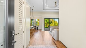 A modern hallway with a wooden floor, a sofa, and a dining area with a view of greenery. - New 3BR , Near Myakka River, Boca Grande + Beach (Port Charlotte)