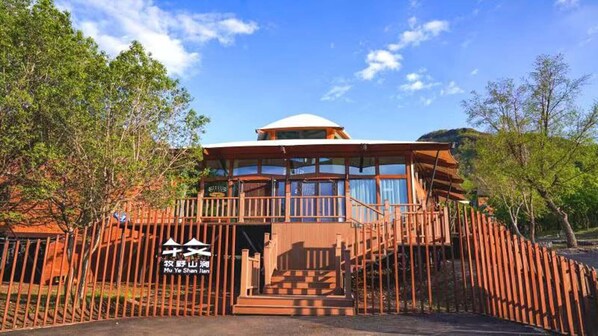 A two-story building with a dome-shaped roof, surrounded by a wooden fence, and a sign with Chinese characters.