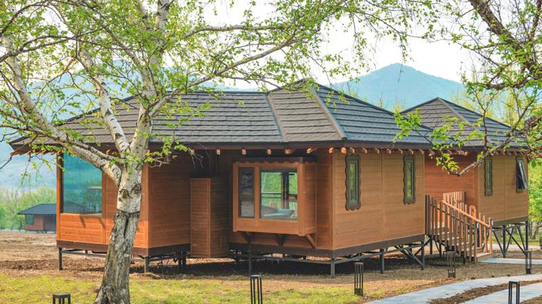 A wooden cabin with a gabled roof, a front porch, and a small staircase leading to the entrance.