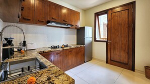 A kitchen with wooden cabinets, a stainless steel sink, a built-in oven, and a refrigerator.