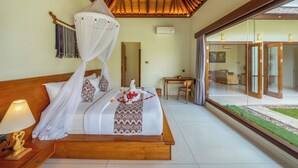 A bedroom with a canopy bed, a desk, and a view of the outdoor area.
