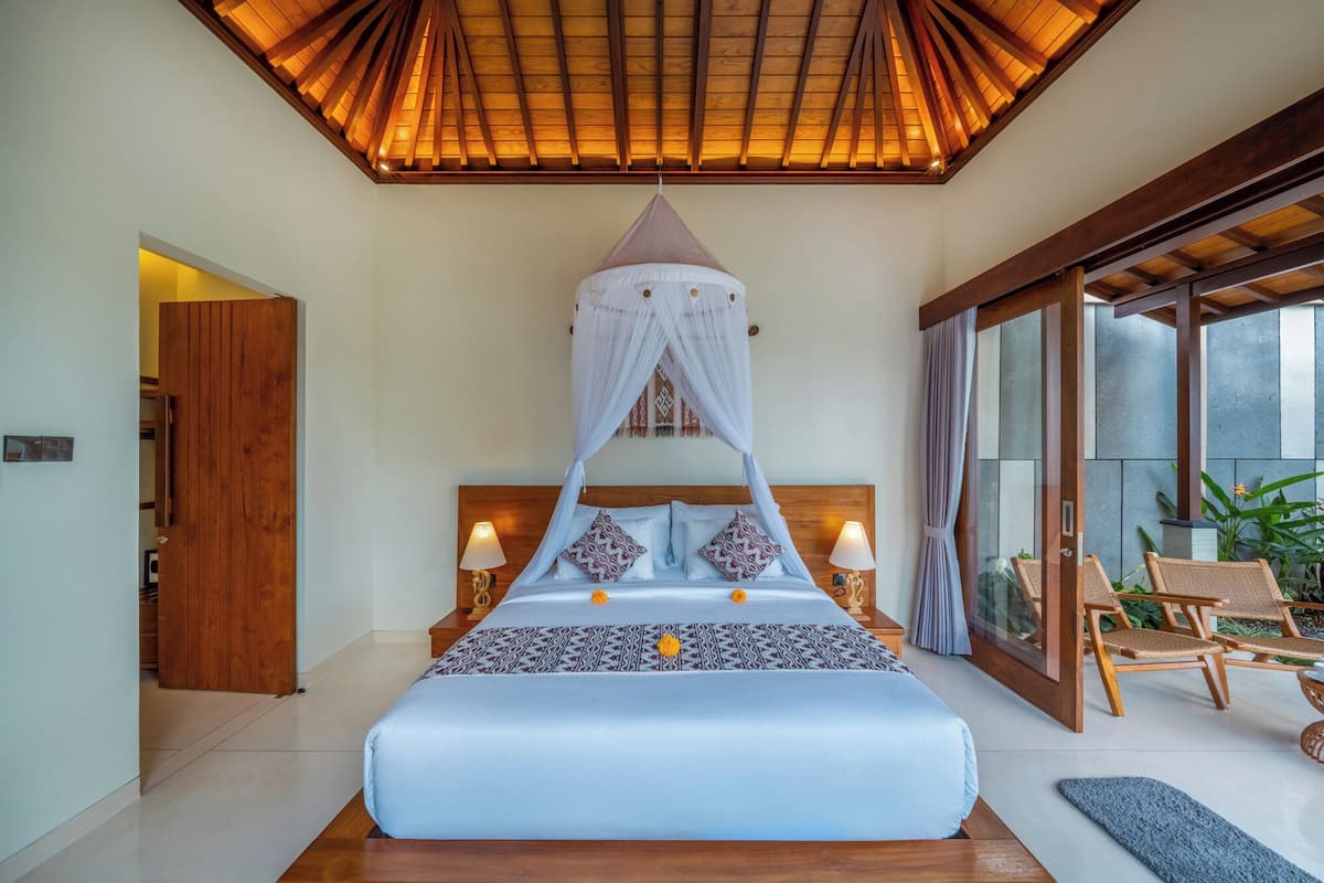 A bedroom with a canopy bed, wooden ceiling, and a view of the outdoors.