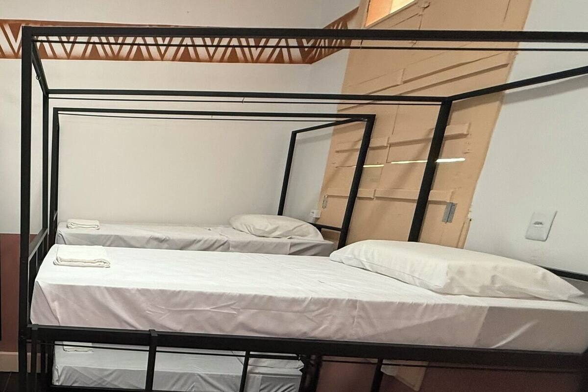 A bunk bed room with three beds, each with white bedding.