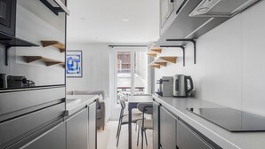 A modern kitchen with grey cabinetry, a coffee machine, and a dining area with a table and chairs. - Blueground | Le Marais, view, nr Place des Vosges (Paris)
