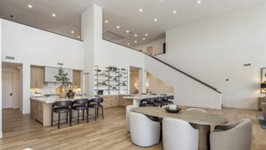 A spacious kitchen with a central island, a dining area with a large table and chairs, and a staircase leading to an upper level. - SWSS Premier 10BR Estate | Pool with Swim‑Up Bar | Golf Simulator | Sport Court | Sauna & Cold Pl... (Scottsdale)