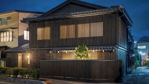 Een traditioneel Japans gebouw met een donker houten gevel, grote ramen en een pannendak.
