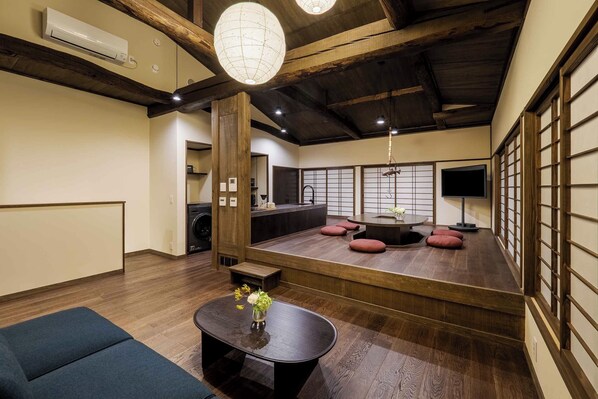 Una habitación tradicional japonesa con suelo de tatami, una mesa baja con un florero y un televisor sobre un soporte.
