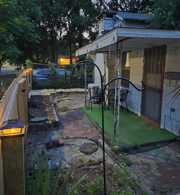 A small house with a patio, outdoor seating, and a garden area.