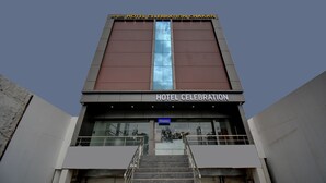 Entrada de un hotel con una recepción, una escalera y un letrero que dice "HOTEL CELEBRATION CHAKAN".