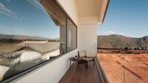 Una habitación moderna con un amplio ventanal que da a un edificio tradicional y un paisaje montañoso.