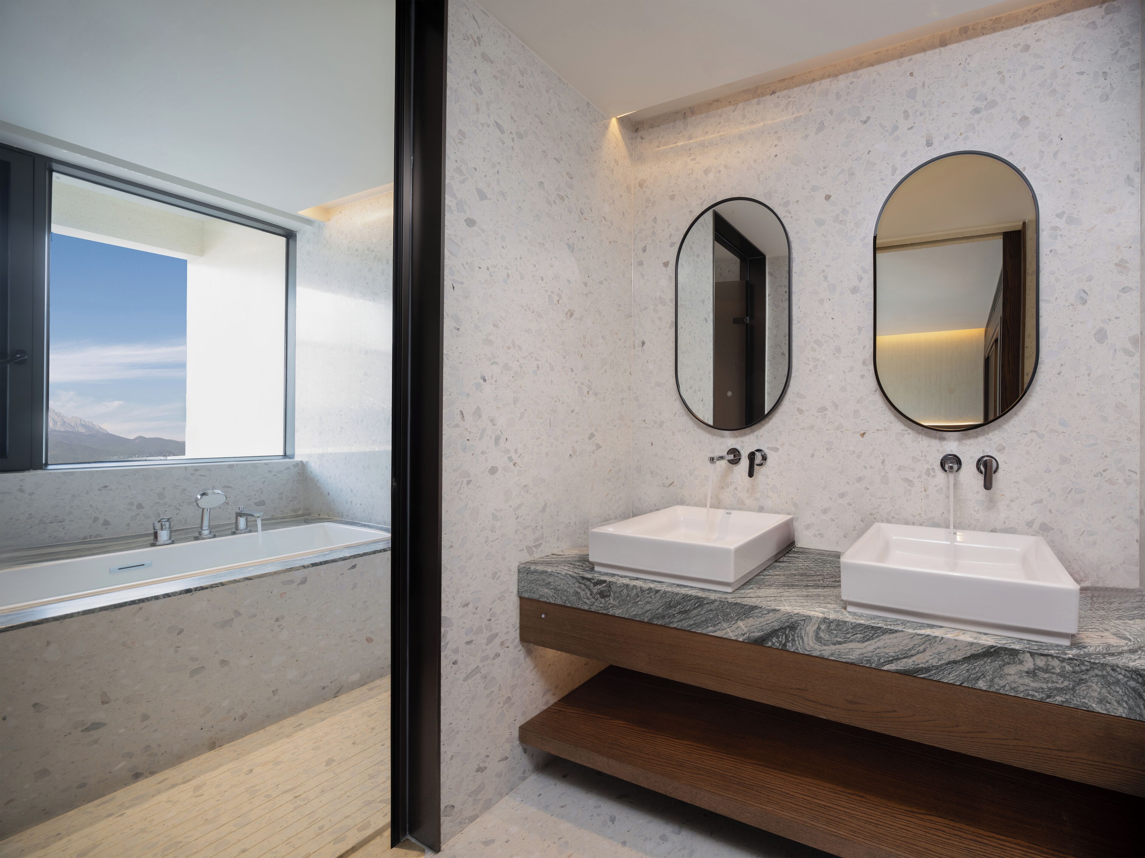 A modern bathroom with a large window, two sinks, and a mirror.