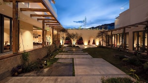 Un edificio moderno con un espacio exterior cubierto, que cuenta con un camino y plantas en macetas.