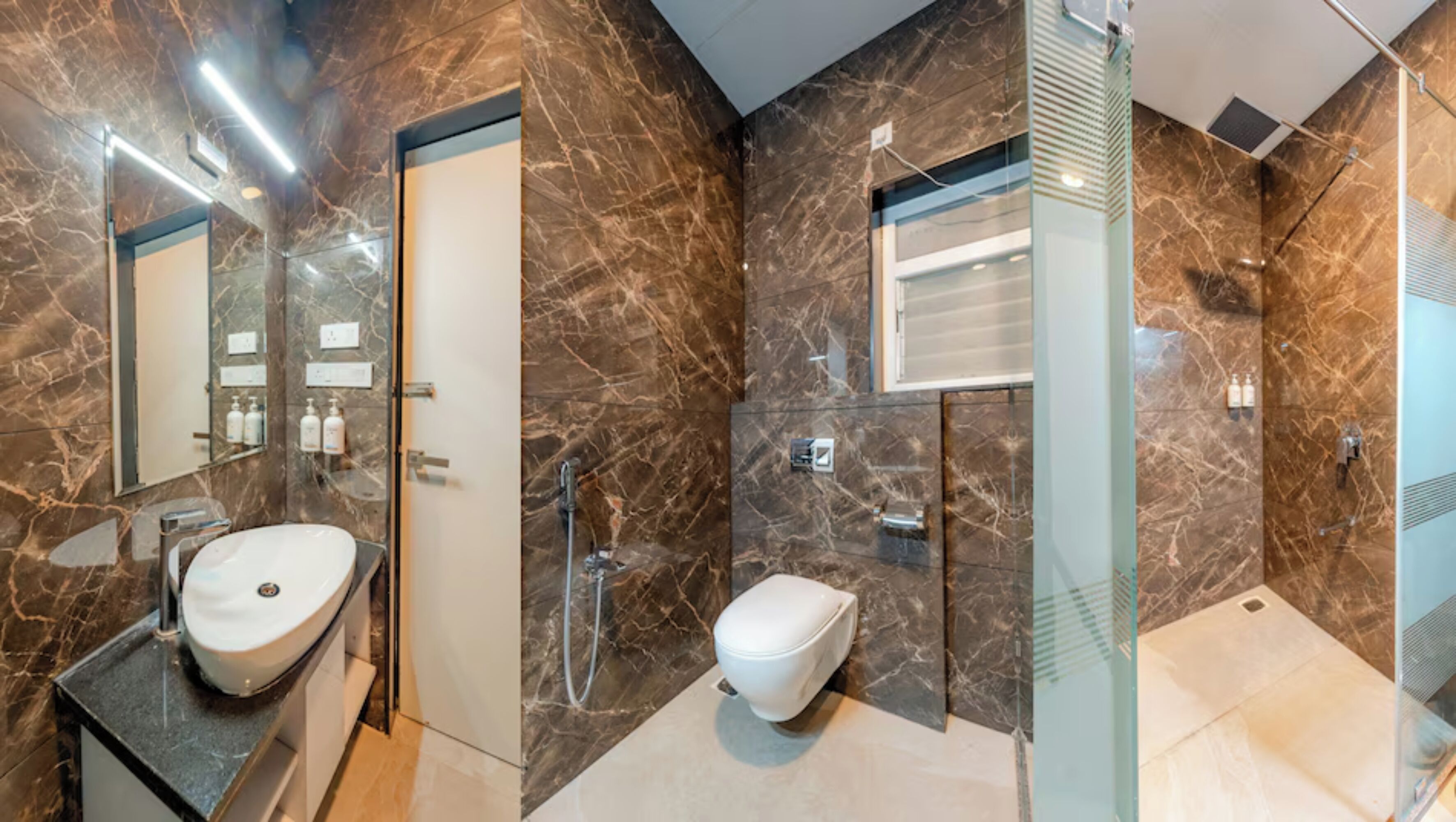 Une salle de bain moderne avec un meuble-lavabo en marbre, des toilettes séparées, une douche à parois de verre et un grand miroir.