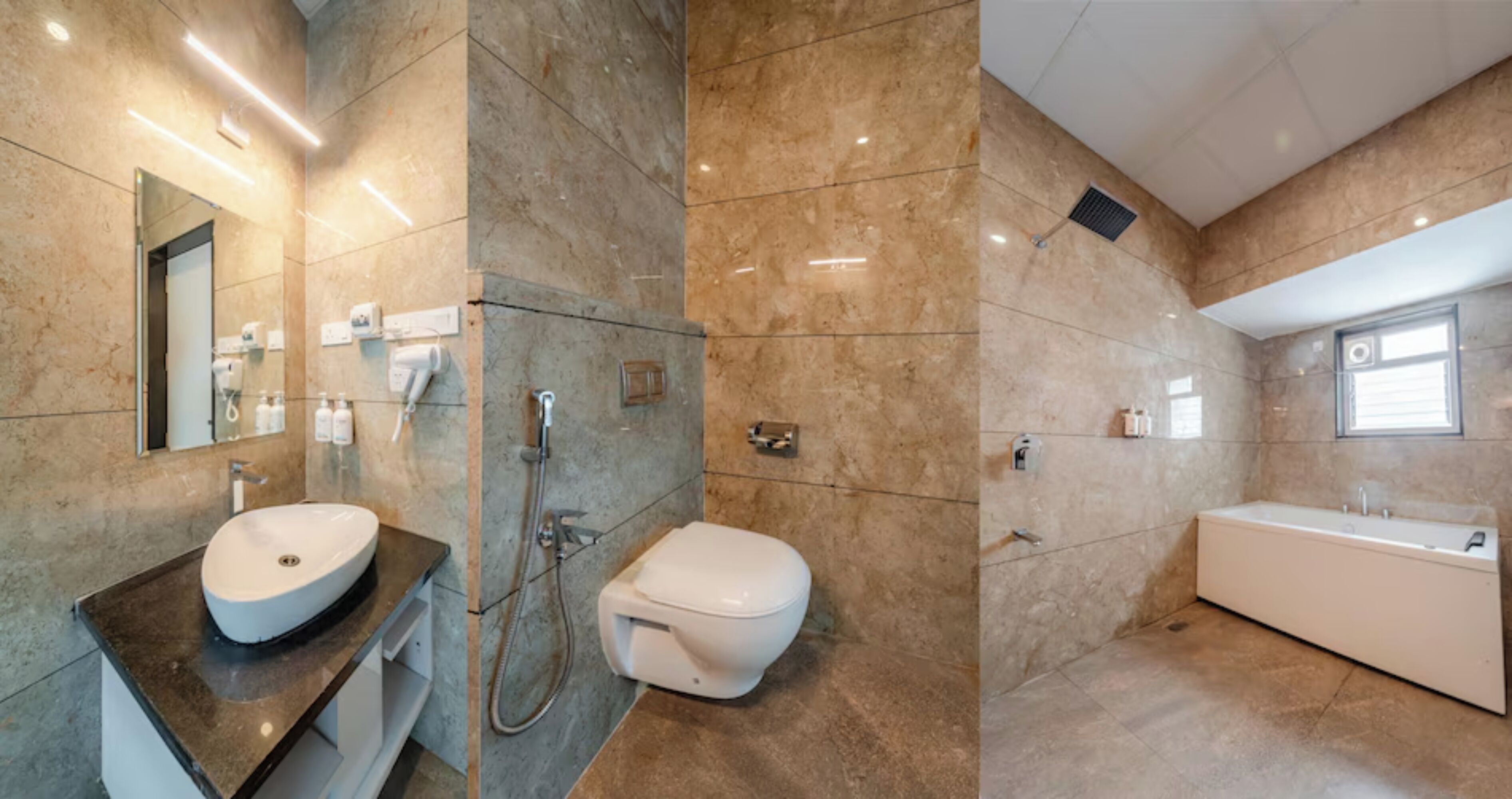 A modern bathroom with a sink, toilet, and bathtub, marble walls, and a large mirror.