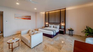 A modern hotel room with a bed, a sofa, a small table, and a ceiling fan. - Pravasa Hotel Vijayapura (Vijayapura)