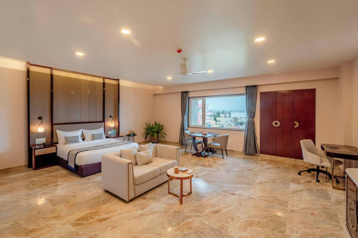 Une chambre d’hôtel moderne équipée d’un lit, d’un canapé, d’un bureau et offrant une vue sur la ville.