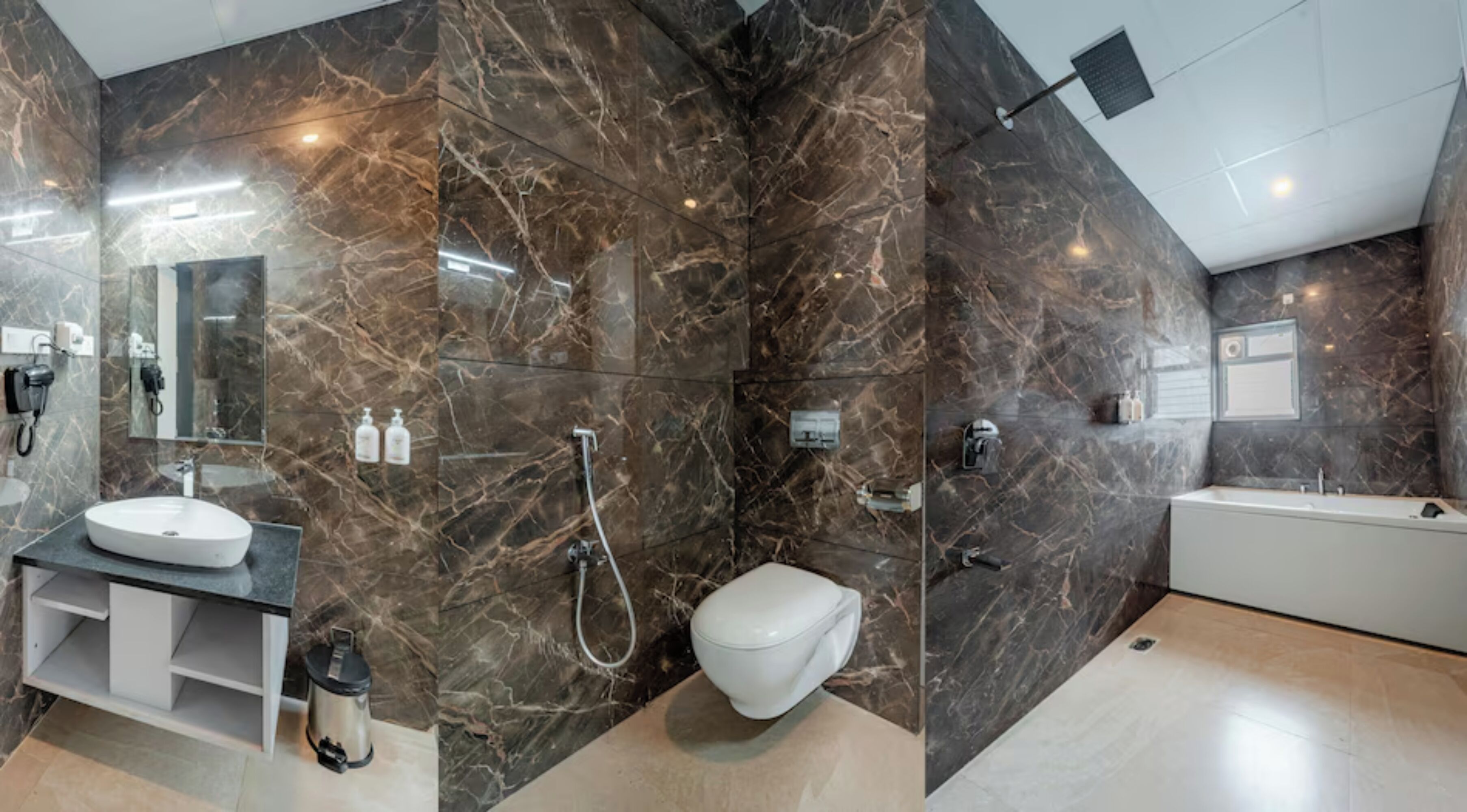 Un baño moderno con pared de mármol, un lavabo blanco, un inodoro y una bañera.