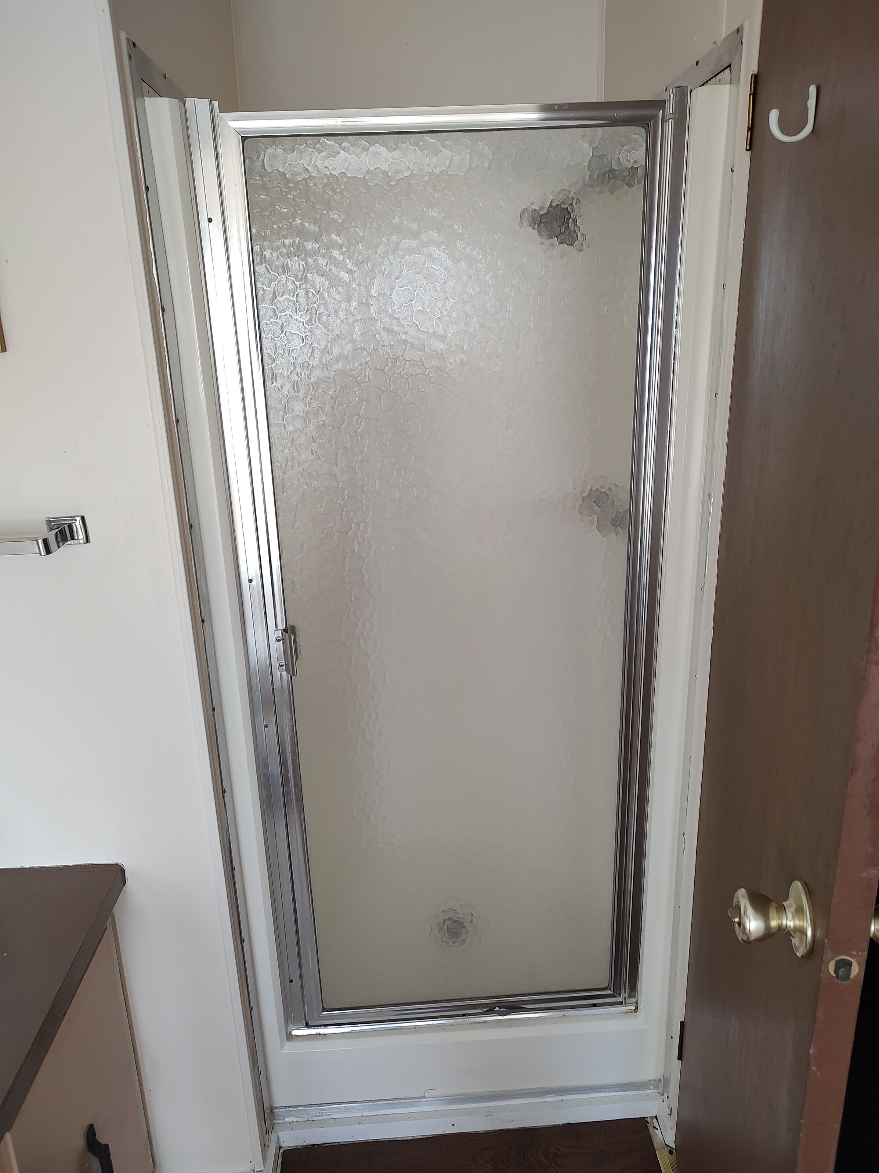 A room with a door that has a frosted glass panel and a metal handle.