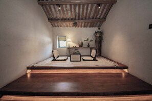 A cozy reading nook with a wooden bench, two chairs, a small table, and a lamp. - Putian City Meizhou Island Bolan Breeze (Putian)