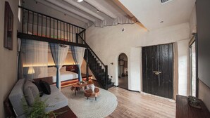 Ein geräumiger Wohnbereich mit Treppe, einer Couch, einem Couchtisch und einem großen Fenster.