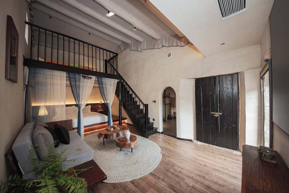 Un vaste espace de vie comprenant un escalier, un canapé, une table basse et une grande fenêtre.