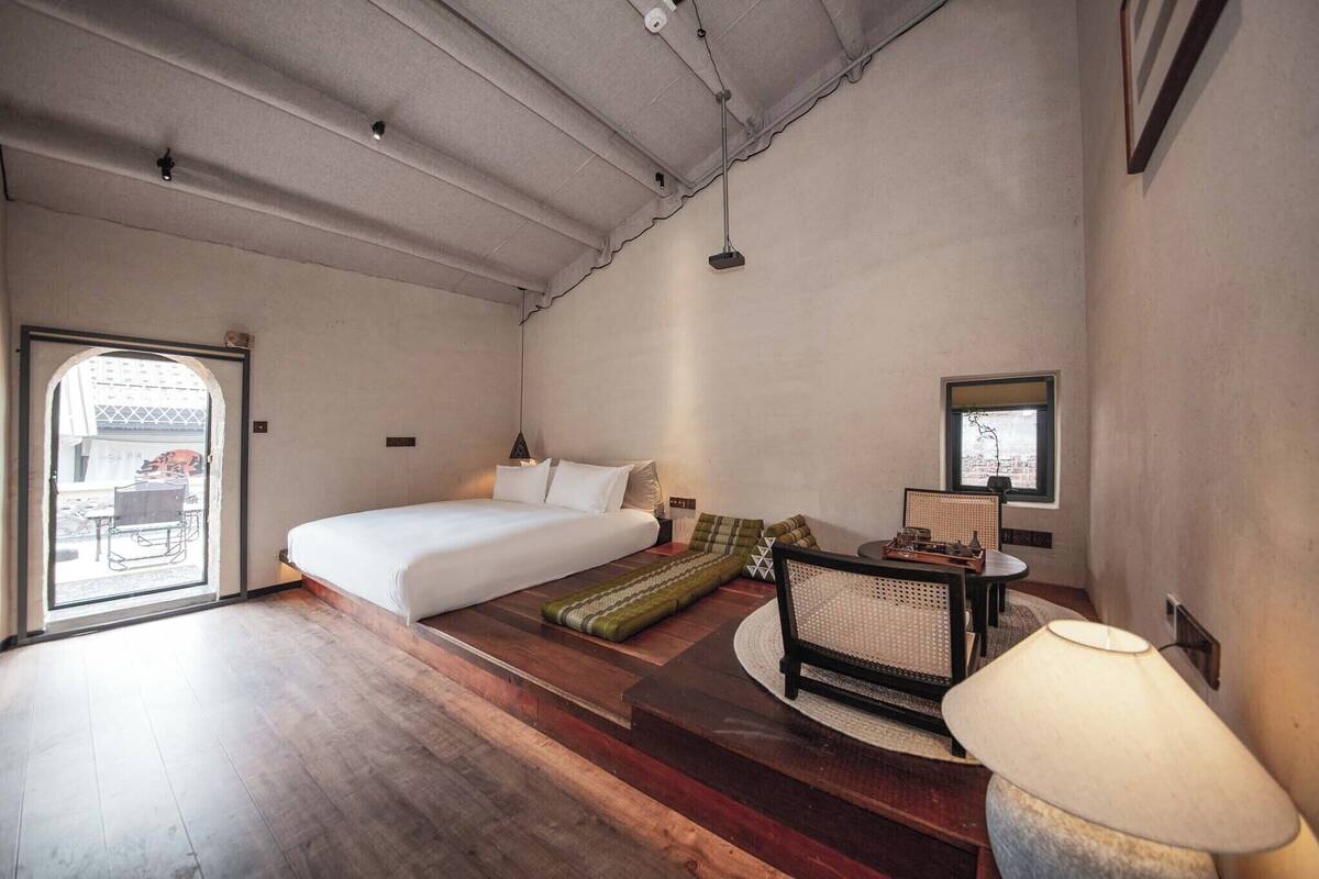 Une chambre à coucher avec un lit, une petite table, une chaise et une fenêtre.